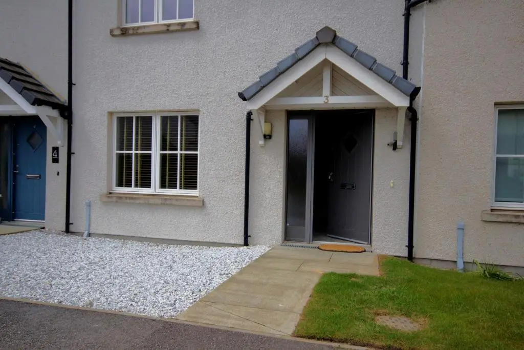 a front door of a white house with a driveway at 3 Mackay Road, Dornoch in Dornoch