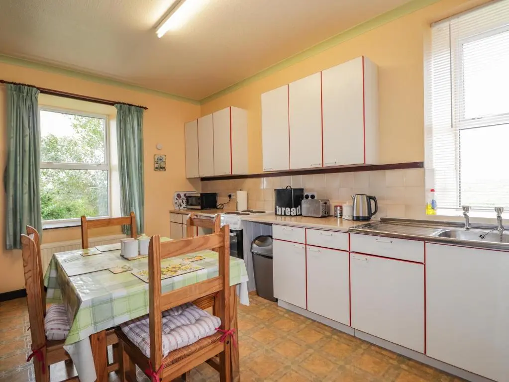 a kitchen with white cabinets and a table and a sink at Star Croft in Wick
