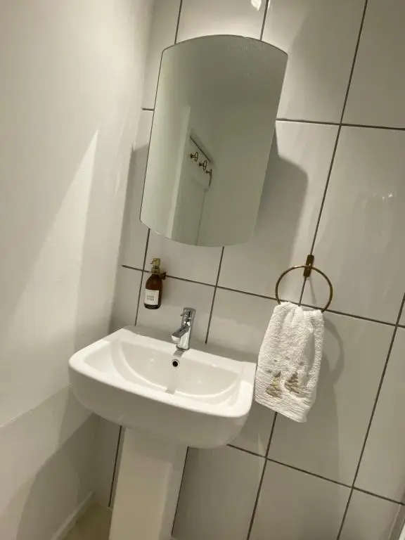 a white bathroom with a sink and a mirror at Brylach Steading in Aberlour