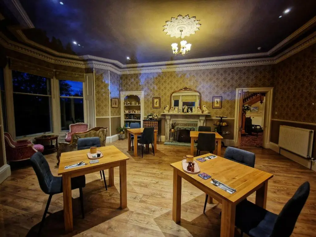 a living room with tables and chairs and a fireplace at The Pines Guest House in Elgin