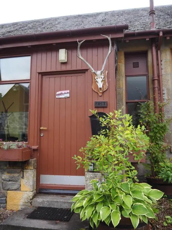 a house with a door with a deer head on it at Uist Cottage in Kingussie