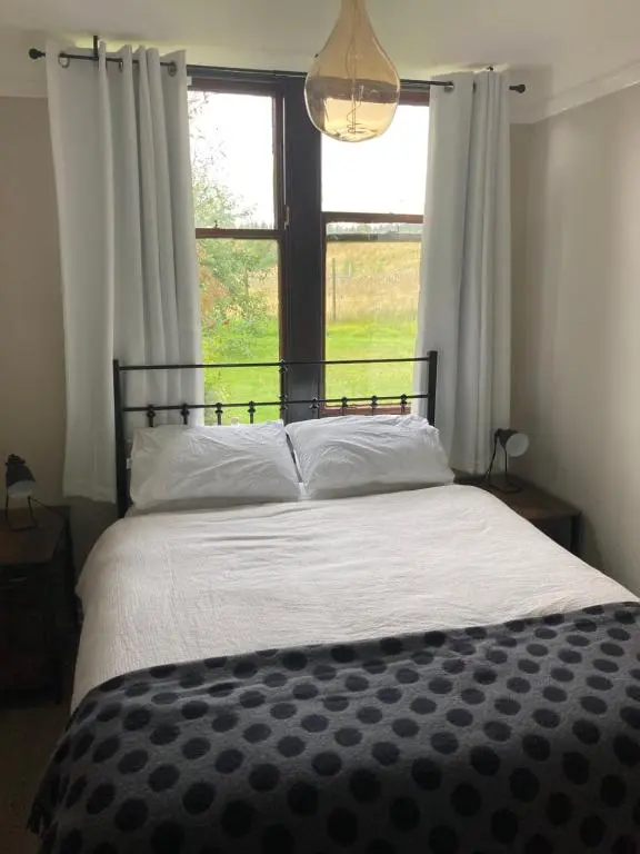 a bedroom with a large bed with a window at Uist Cottage in Kingussie