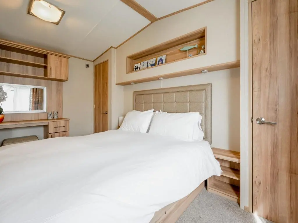 a bedroom with a white bed and a kitchen at Holiday Home Golf View by Interhome in Nairn