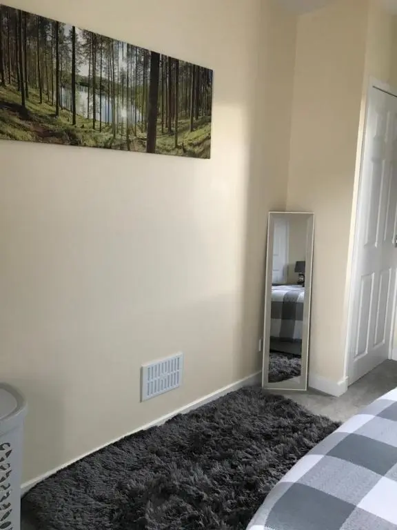 a bedroom with a mirror and a painting on the wall at No 5 Newly refurbished 4 bedroom house in Cononbridge