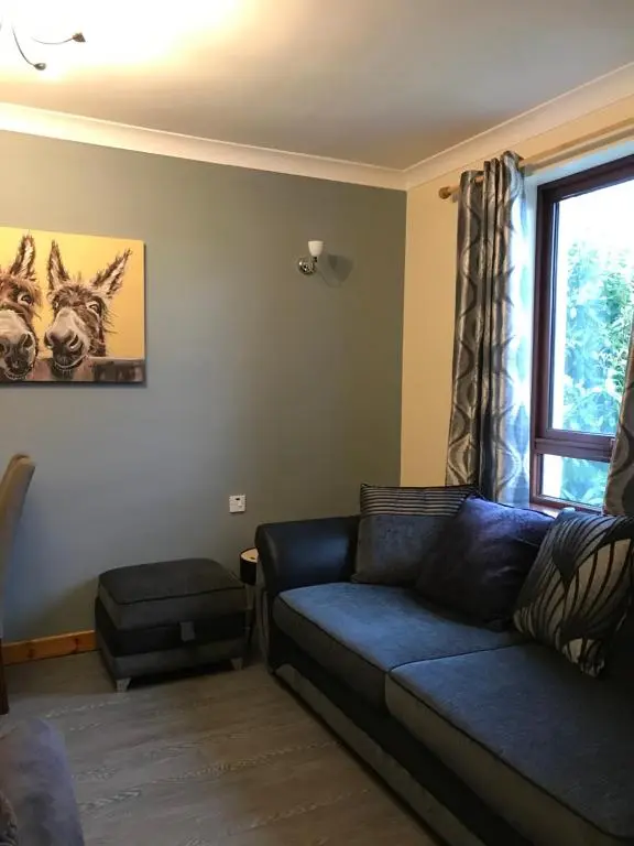 a living room with a blue couch and a window at No 5 Newly refurbished 4 bedroom house in Cononbridge