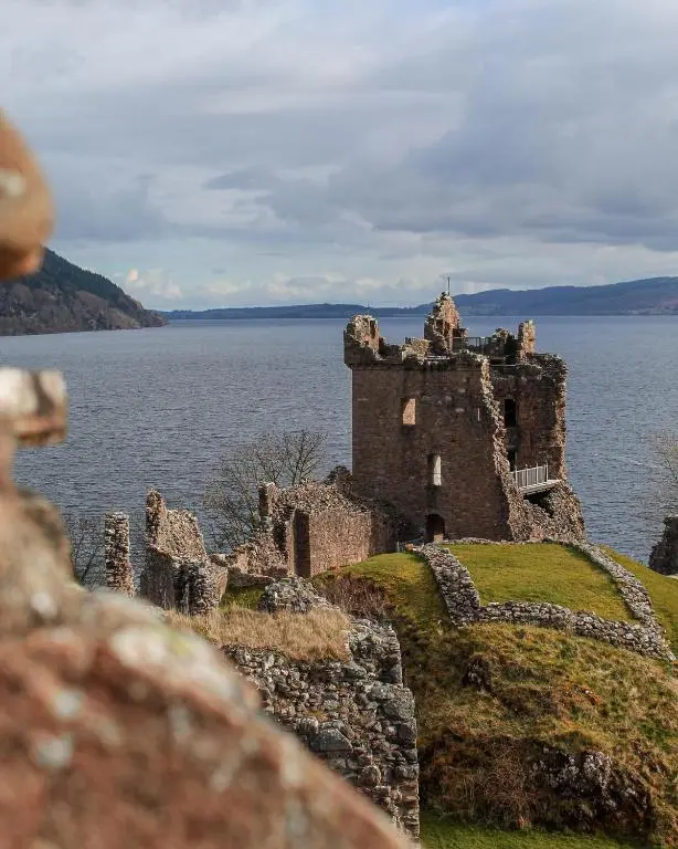 an old castle on the edge of a body of water at Stylish Garden Flat Near Loch Ness in Drumnadrochit