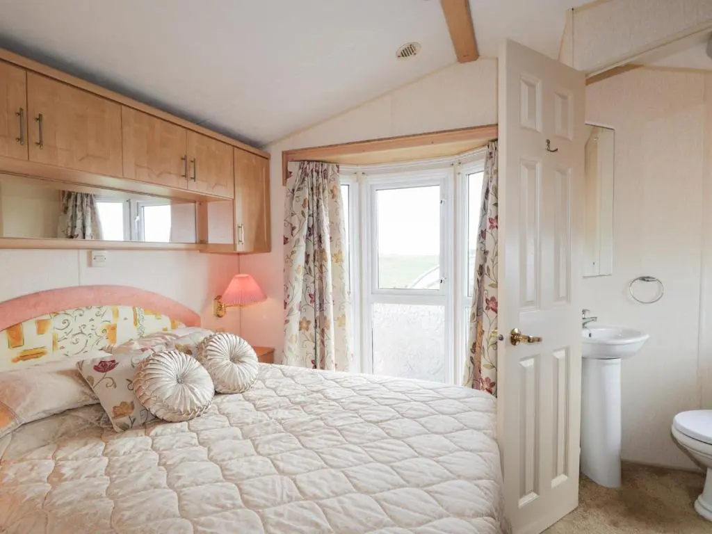 a bedroom with a bed and a sink and a window at The Cabin in Lybster