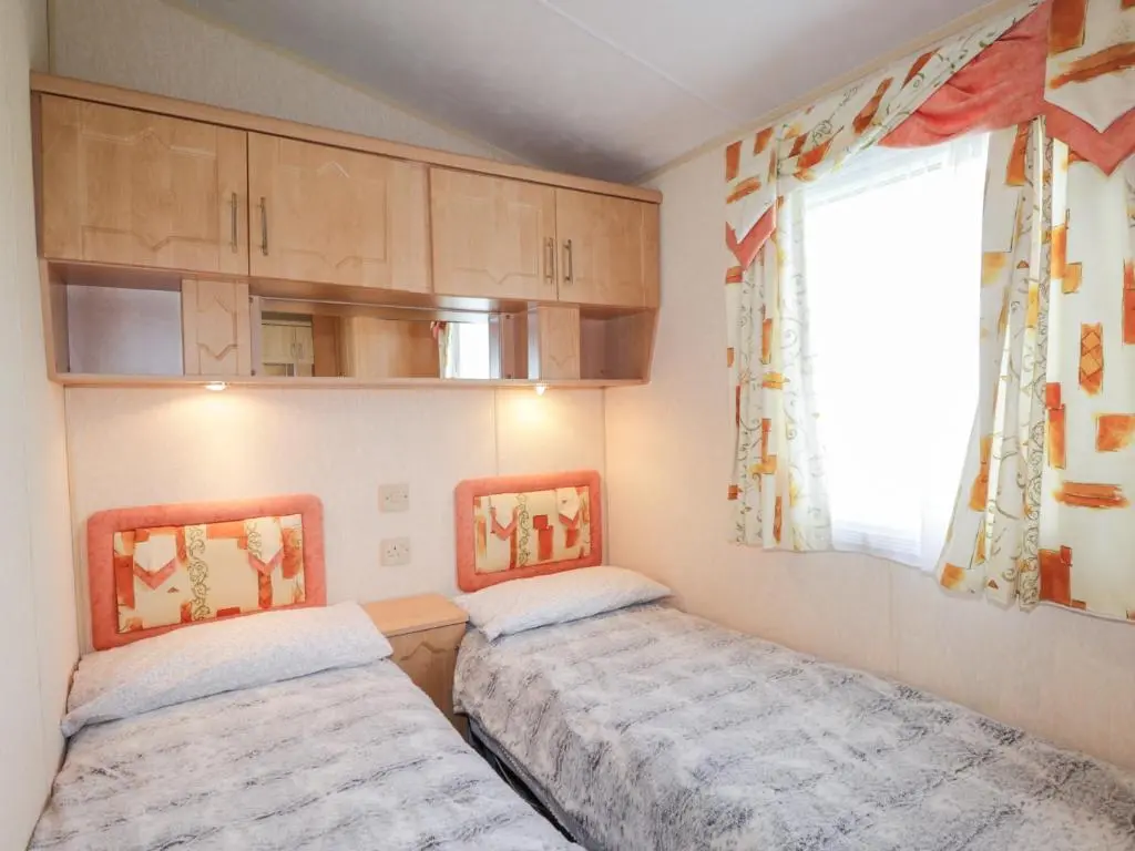 a small bedroom with two beds and a window at The Cabin in Lybster
