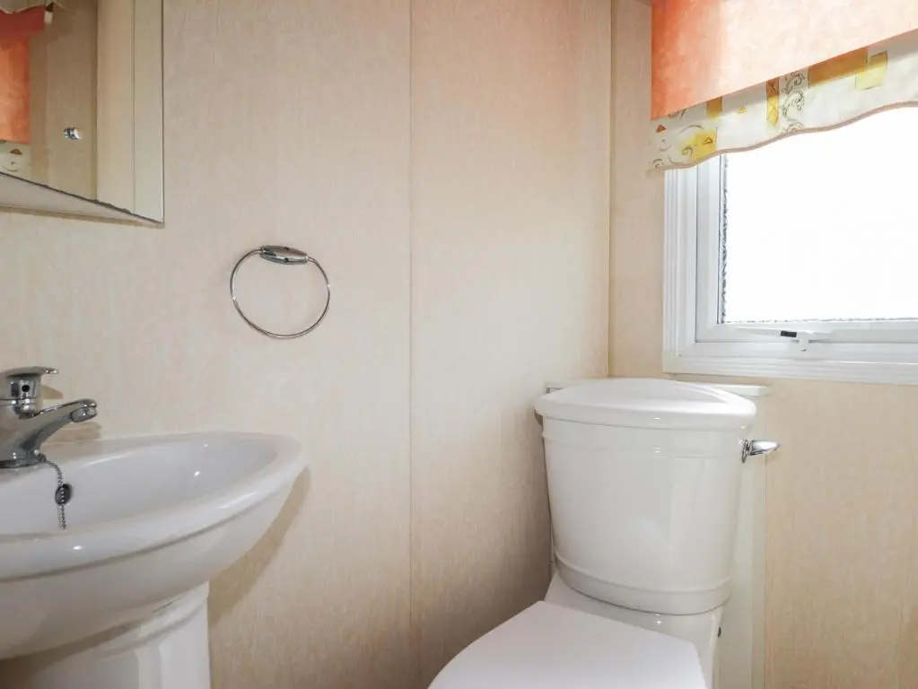a bathroom with a white toilet and a sink at The Cabin in Lybster
