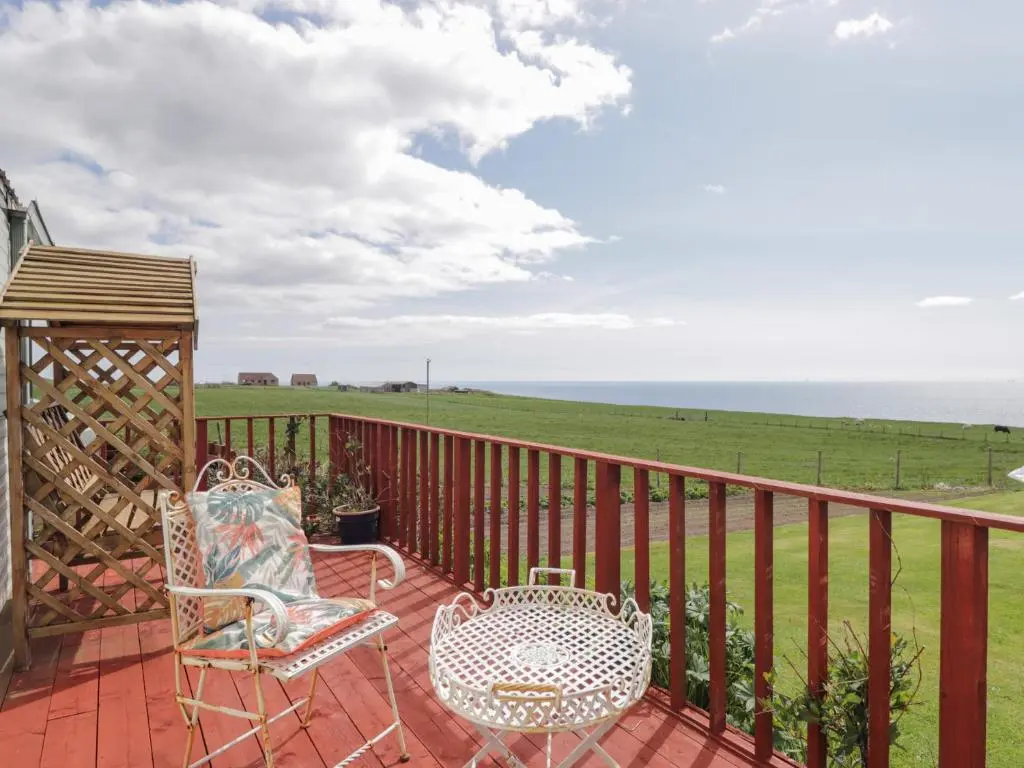 a balcony with two chairs and a gazebo at The Cabin in Lybster