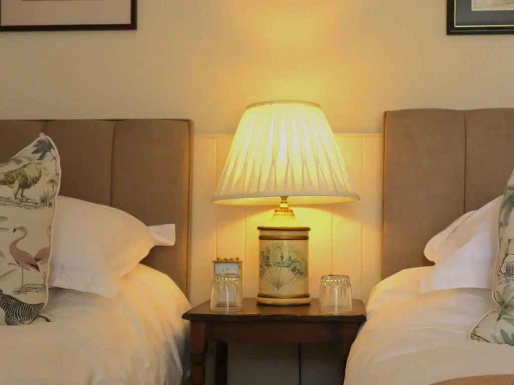 a lamp on a table next to two beds at Mains of Orton in Fochabers