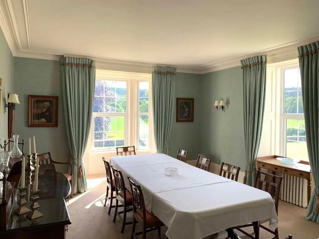a dining room with a table and chairs and windows at Mains of Orton in Fochabers
