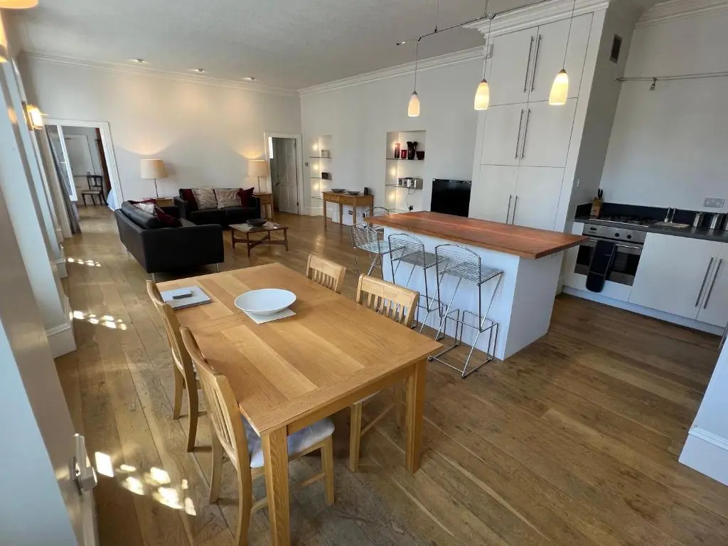a kitchen and living room with a wooden table and chairs at Central 1-Bed Apartment in Inverness Sleeps 4 in Inverness