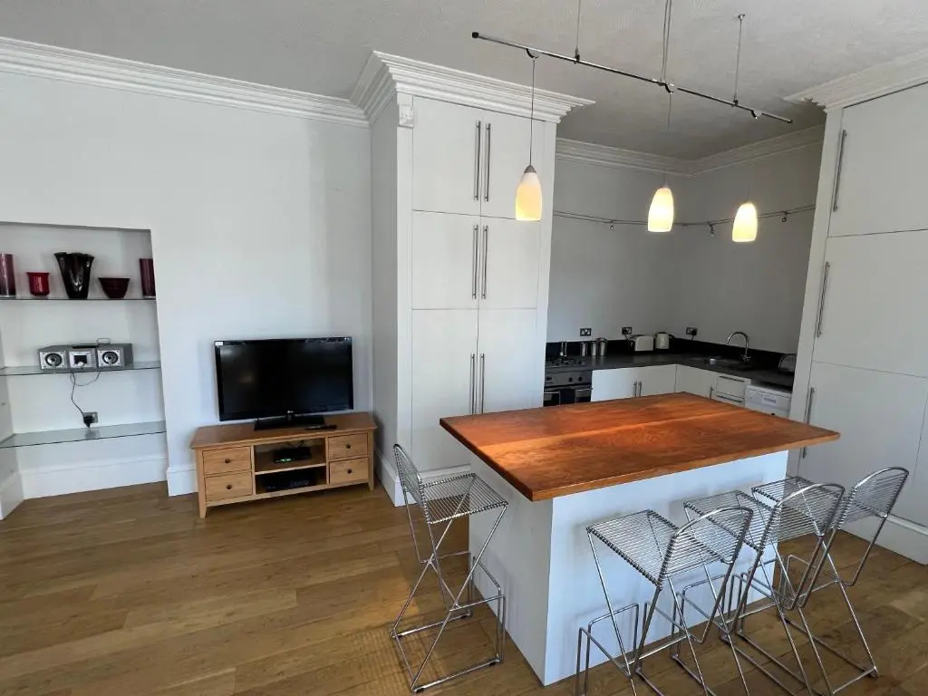 a kitchen with a island with chairs and a television at Central 1-Bed Apartment in Inverness Sleeps 4 in Inverness