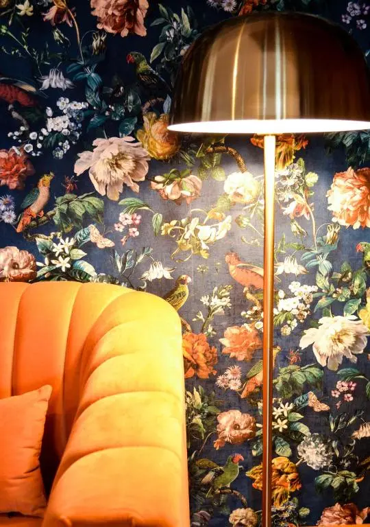 a lamp sitting next to a couch with a floral wallpaper at The Tower, Moray Firth Holiday Home in Kinloss
