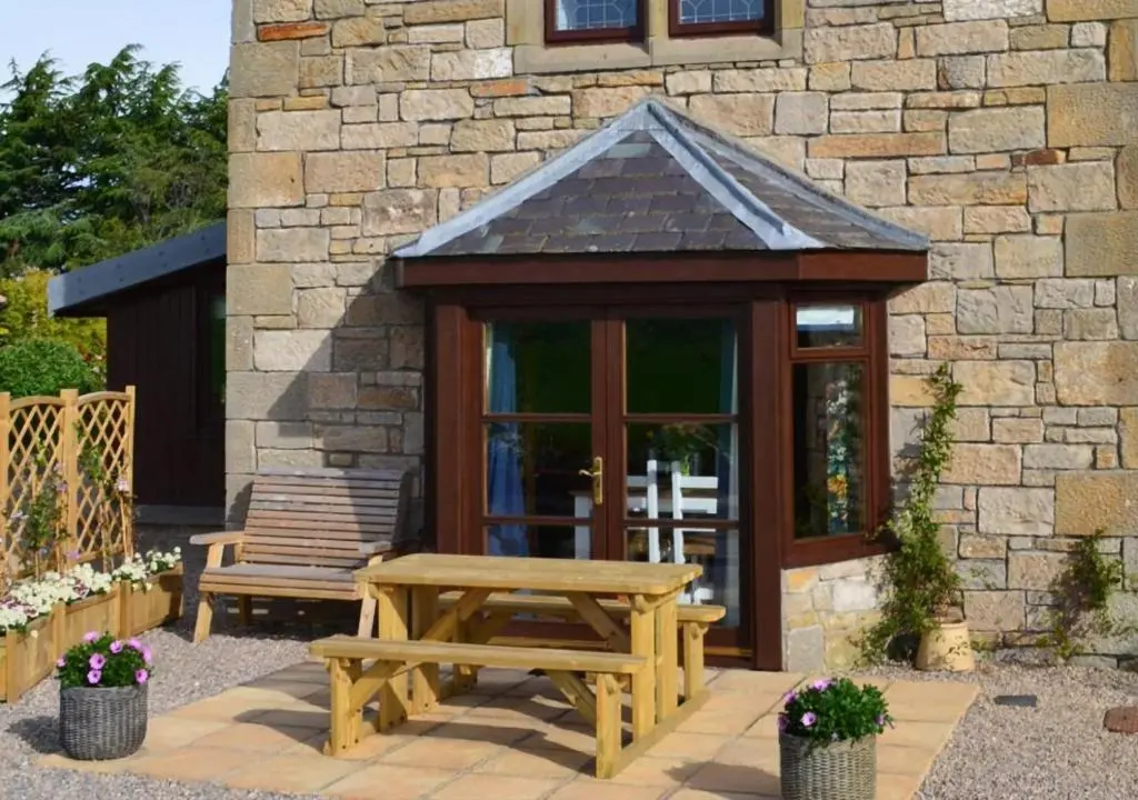 a picnic table and a bench in front of a building at The Tower, Moray Firth Holiday Home in Kinloss