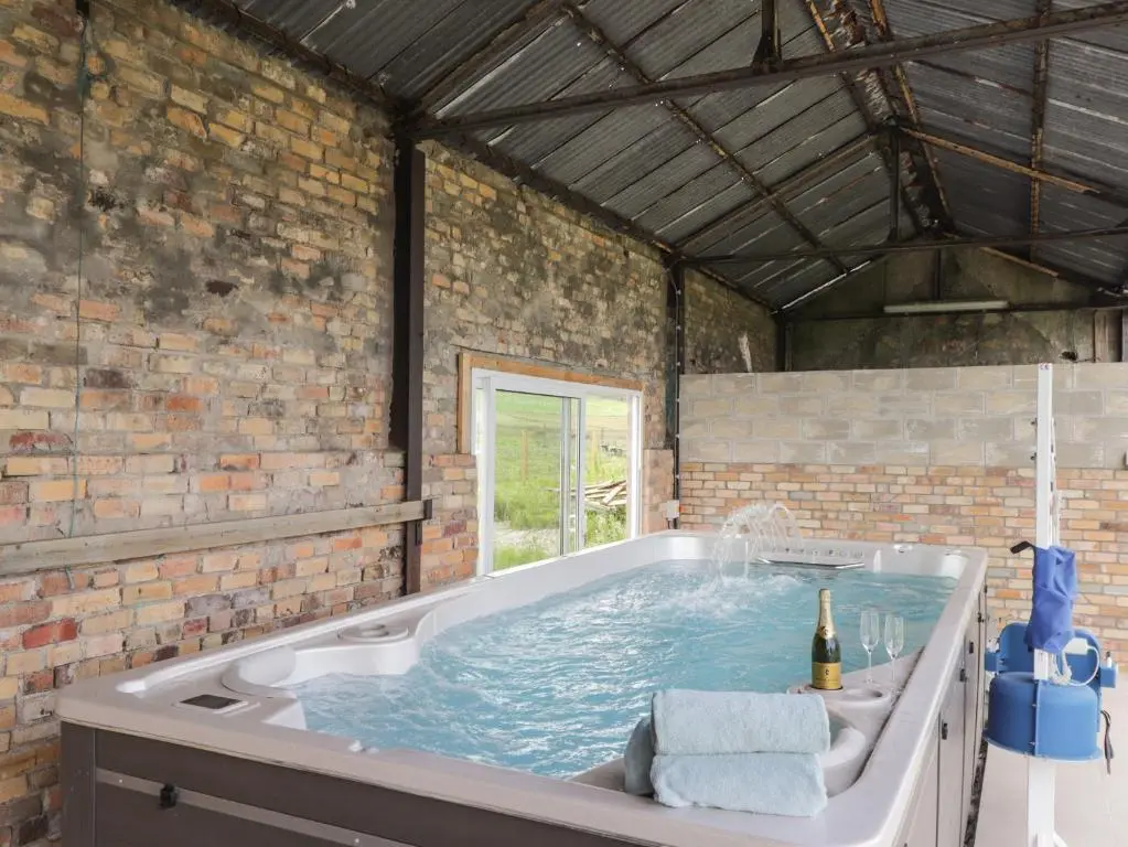 a large bath tub with a bottle of wine in it at Moss of Bourach in Aberlour