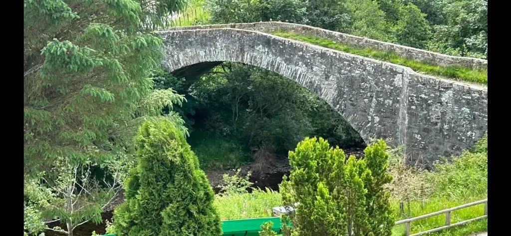 a stone bridge over a river in a forest at The Guest suite at Daviot ,Inverness in Inverness