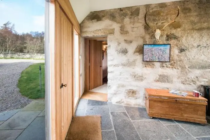 a room with a stone wall and a wooden table at Clashindeugle Farmhouse & Annex in Grantown on Spey