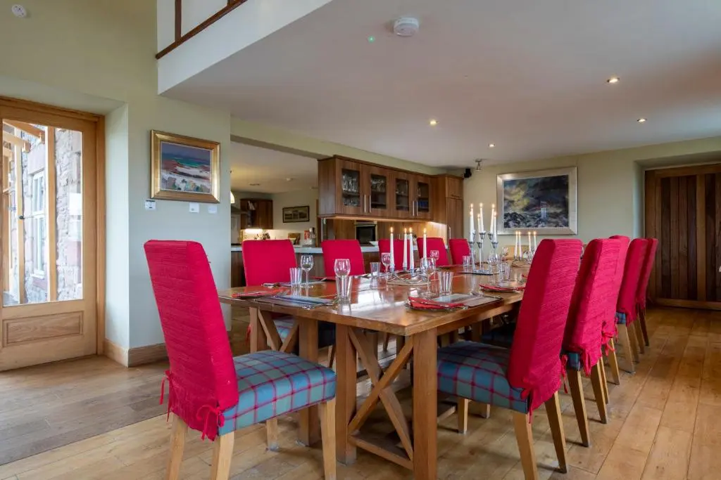 a dining room with a wooden table and red chairs at Quarryfield in Inverness