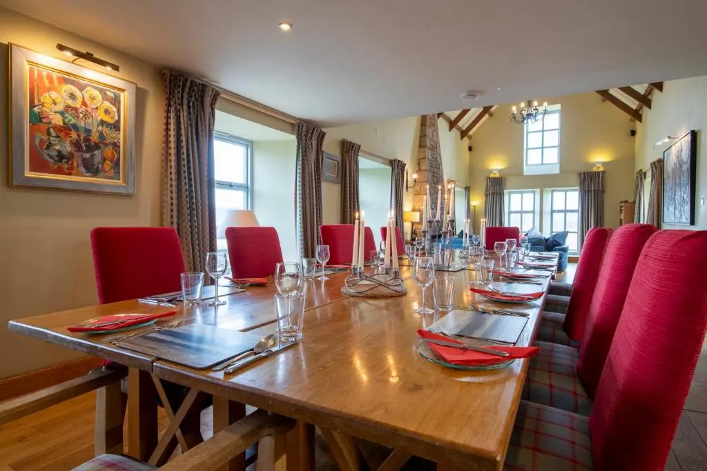 a long wooden table with red chairs around it at Quarryfield in Inverness