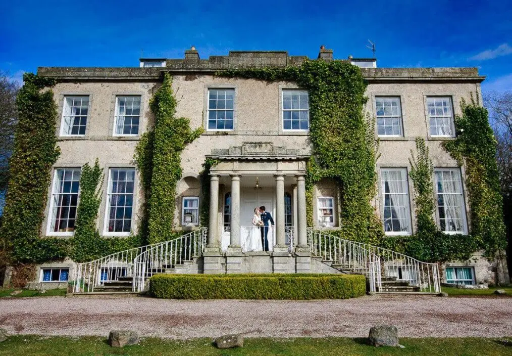 a bride and groom standing on the steps of a building at Cortes House in Fraserburgh