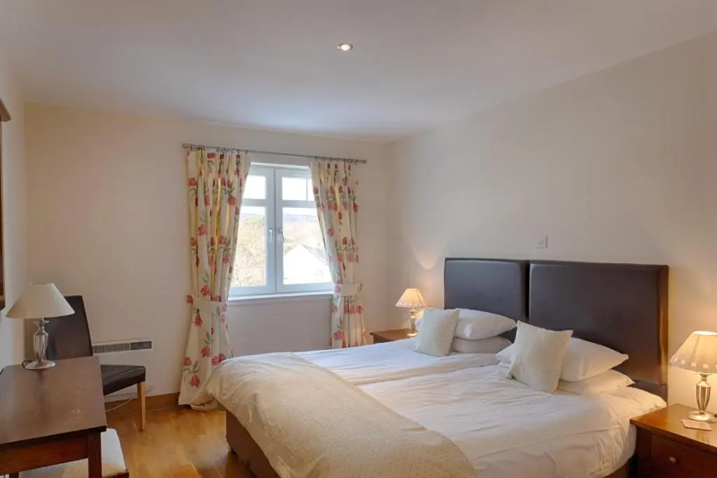a bedroom with a large bed and a window at Links Apartment in Brora