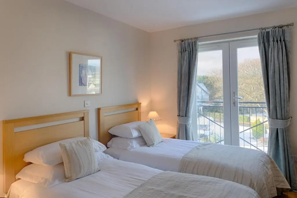 two beds in a hotel room with a balcony at Links Apartment in Brora