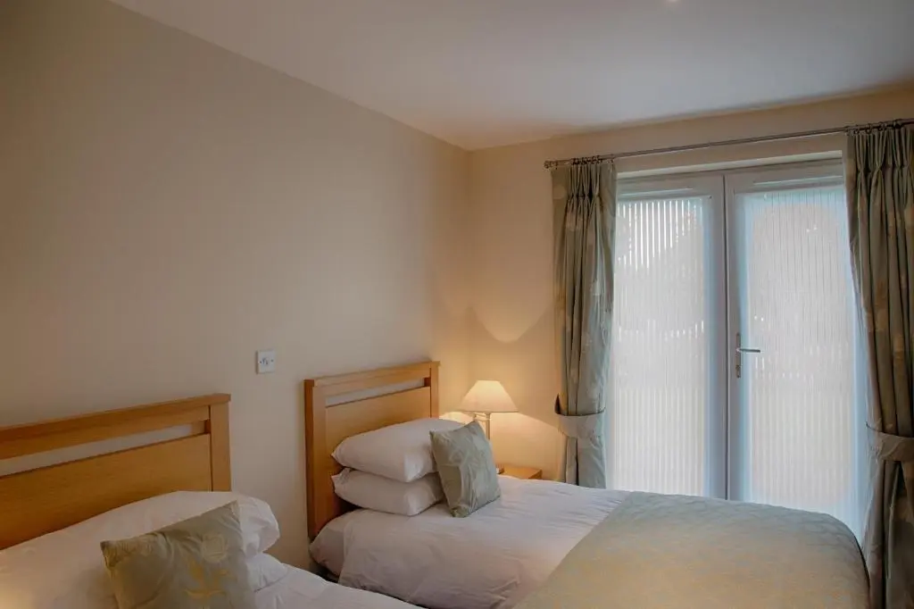 two beds in a room with a window at Links Apartment in Brora