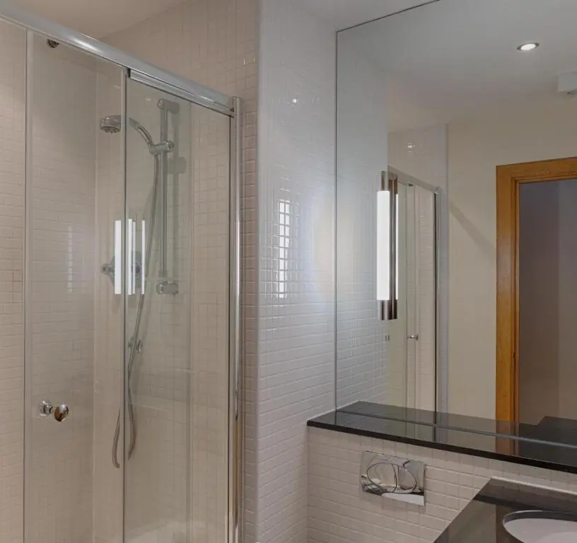 a bathroom with a shower with a sink and a mirror at Links Apartment in Brora