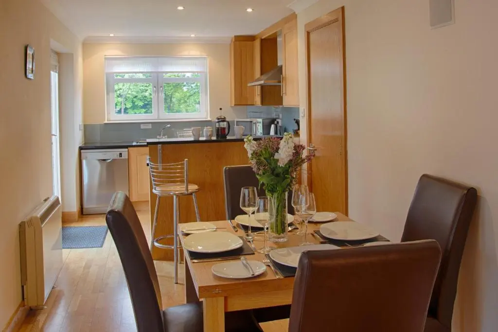 a dining room table with chairs and a kitchen at Links Apartment in Brora