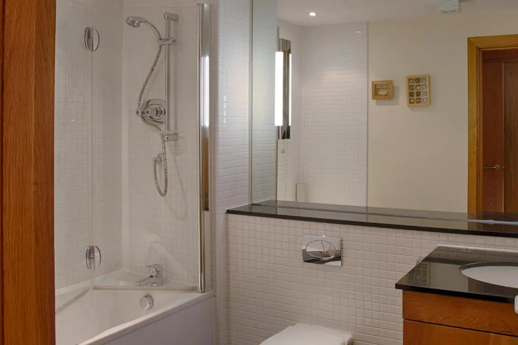 a bathroom with a shower and a tub and a sink at Links Apartment in Brora