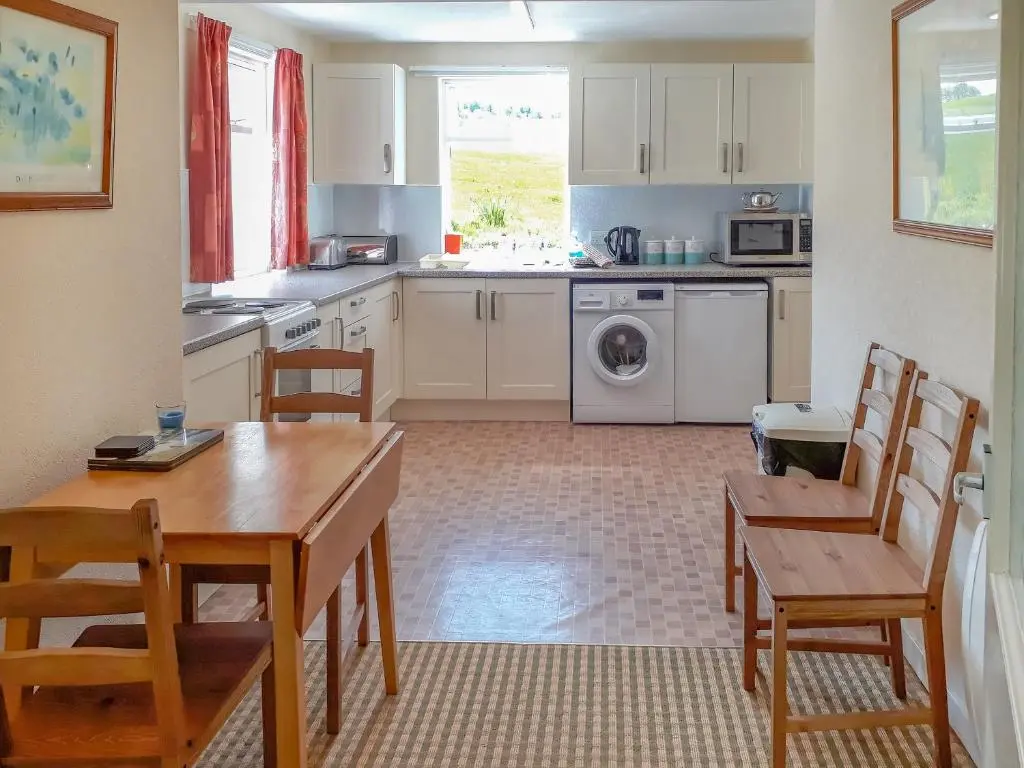 a kitchen with a table and chairs and a dining room at Ivy Cottage in Mountblairy