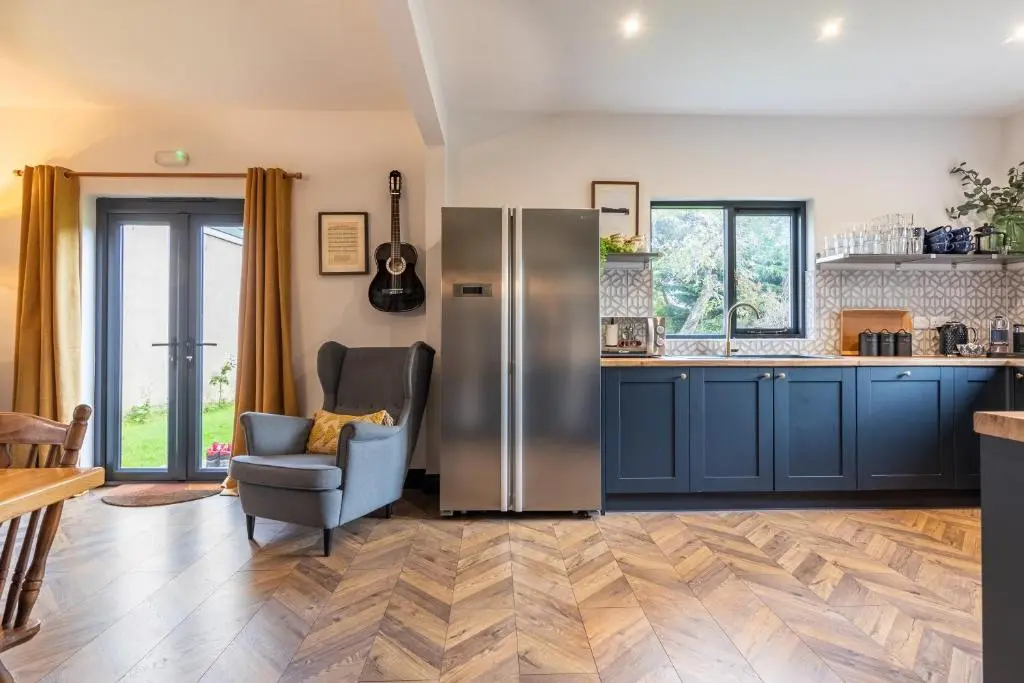 a kitchen with blue cabinets and a stainless steel refrigerator at Ness on the Lane in Inverness