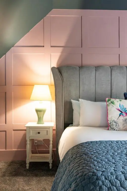 a bedroom with a bed with a pink headboard at Ness on the Lane in Inverness
