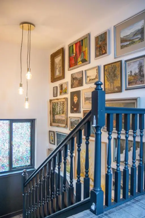 a hallway with a staircase with paintings on the wall at Ness on the Lane in Inverness