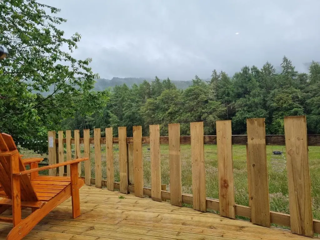 a wooden deck with a bench and a fence at Cozy Nook in Spean Bridge