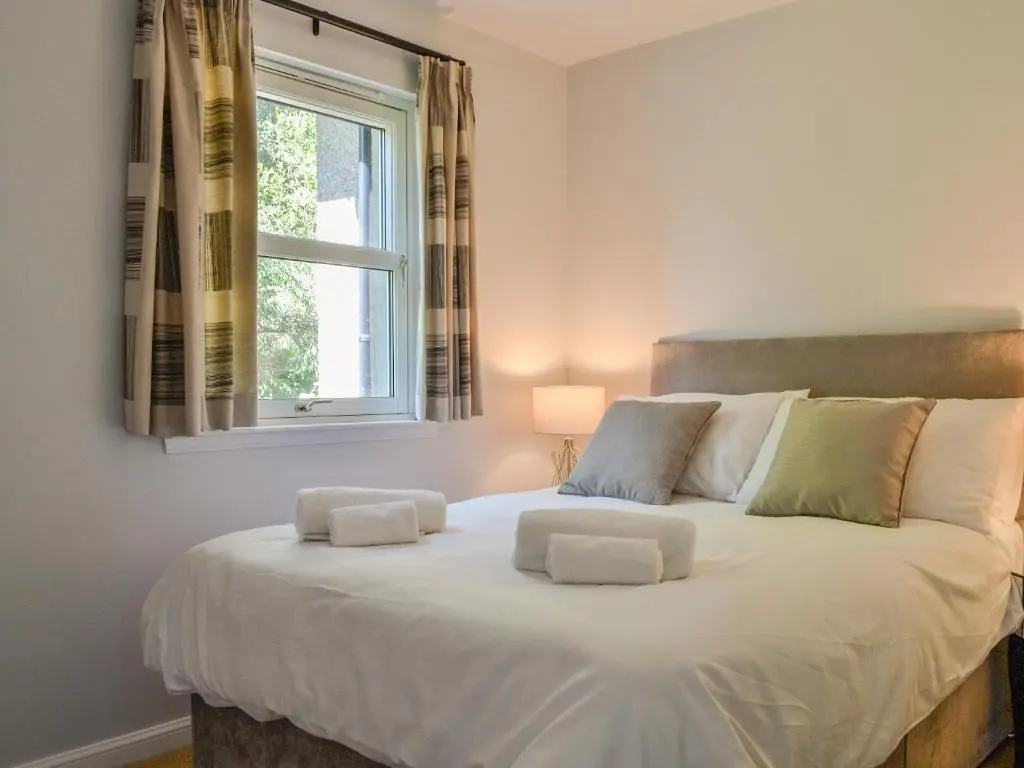 a bedroom with a large white bed with a window at Queen's View Lodge in Inchmarlo