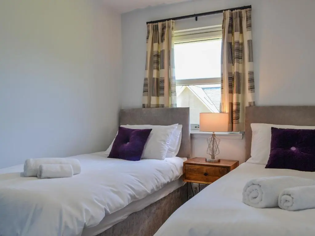 two twin beds in a room with a window at Queen's View Lodge in Inchmarlo