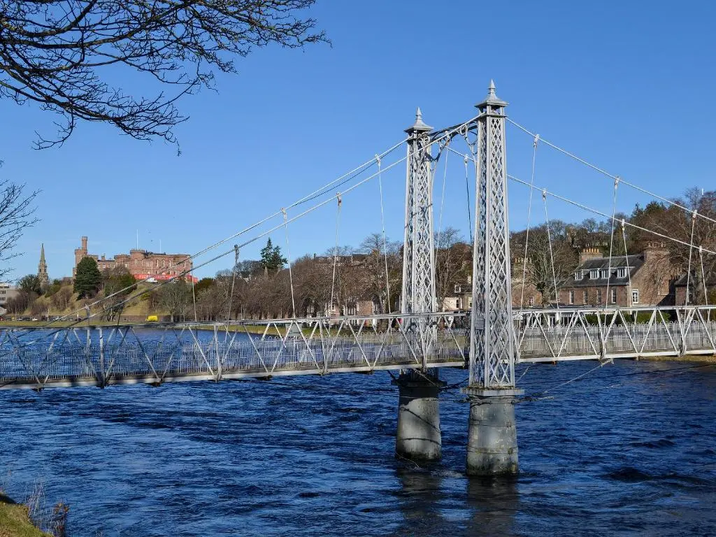 a suspension bridge over a river with water at Ness-Side Apartment in Inverness