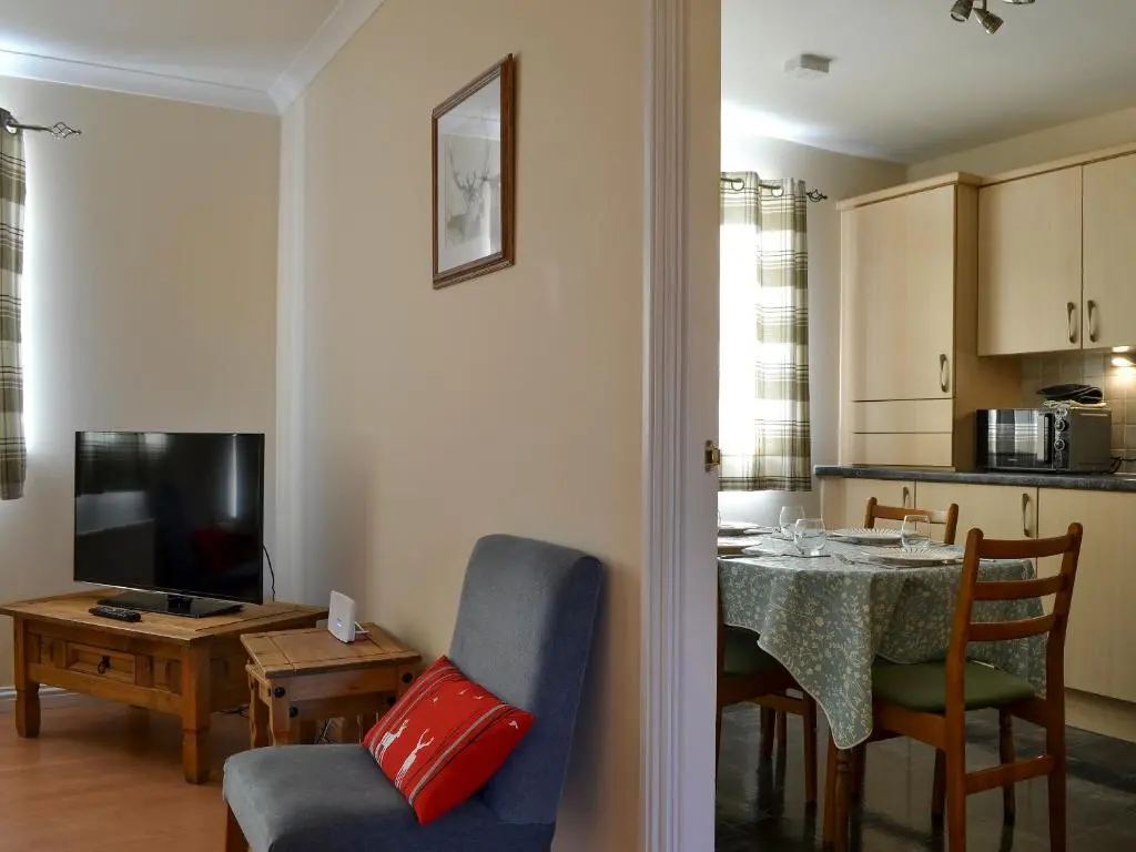 a living room with a table and a dining room at Ness-Side Apartment in Inverness