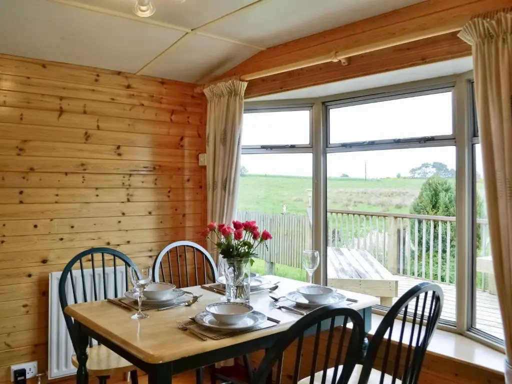 a dining room with a table and chairs and a window at Henrys Lodge in Balblair