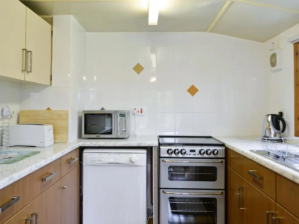 a kitchen with a stove and a microwave at Henrys Lodge in Balblair