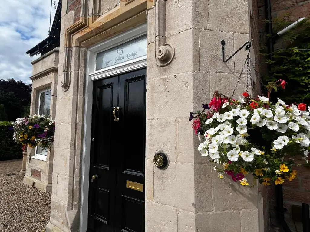 a building with a black door with flowers on it at Beinn Mhor Lodge, 63 Culduthel Road in Inverness