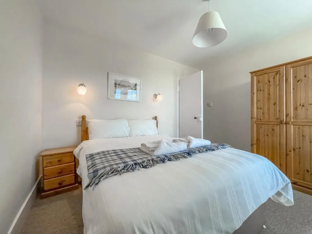 a bedroom with a large white bed and a wooden cabinet at Rowan Cottage - Uk38991 in Dalcross