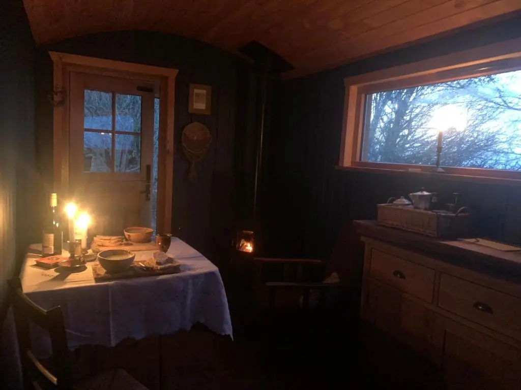 a room with a table with a candle and a window at Birkenshaw - Beautiful Shepherd\u2019s Hut in the Highlands. in Dornoch