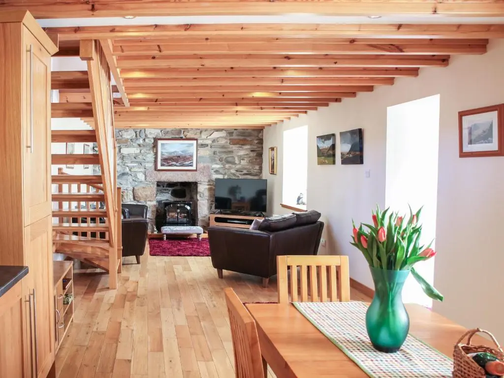 a living room with a staircase and a living room with a table at Hill Cottage in Ardmair