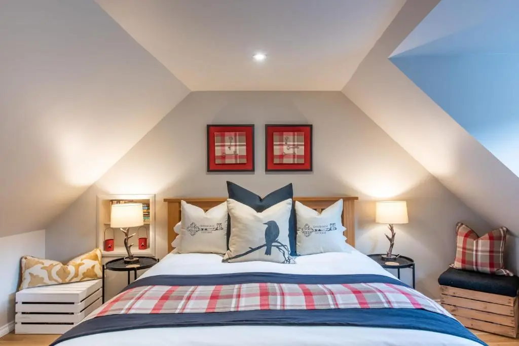 a bedroom with a large bed with two lamps at Crossroads Cottage in Drumnadrochit