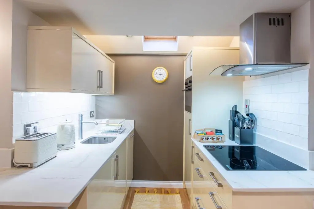 a kitchen with white counter tops and a sink at Crossroads Cottage in Drumnadrochit