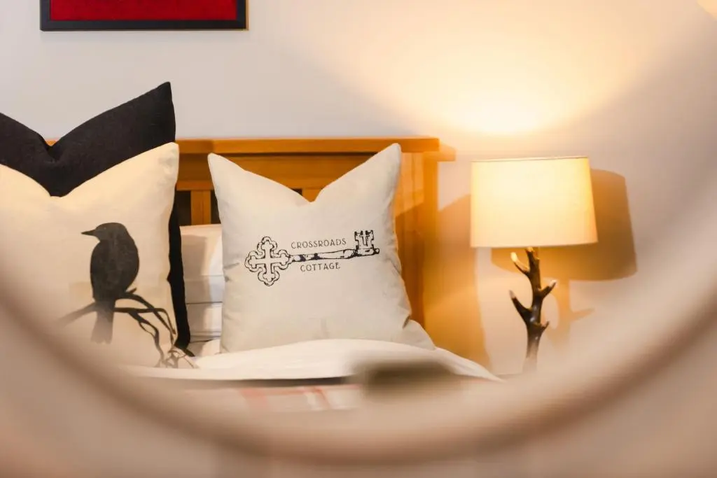 a bedroom with a bed with a pillow and a lamp at Crossroads Cottage in Drumnadrochit